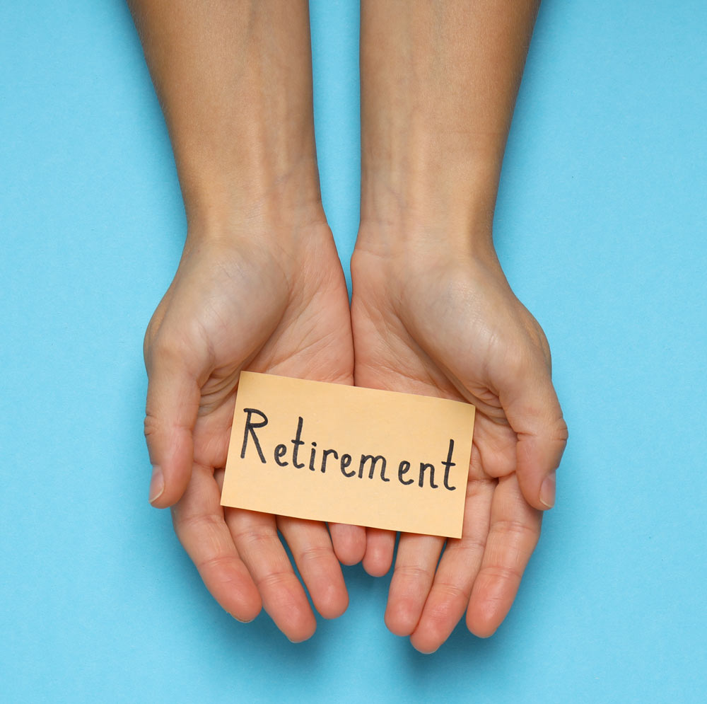 female-hands-holding-paper-with-text-retirement-blue-background